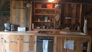 A rustic kitchen with wooden cabinets, a gas stove, a coffee maker, and various kitchen utensils. - 100 years old  BARN revovated (Castets)