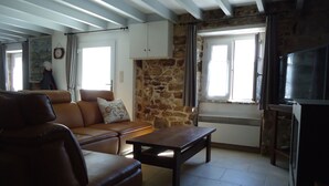 A living room with a brown leather sofa, a wooden coffee table, and a stone wall.