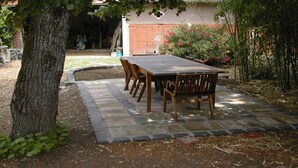 An outdoor patio with a stone pathway leading to a wooden table and chairs. - Country house Bedroom B (Lasgraisses)