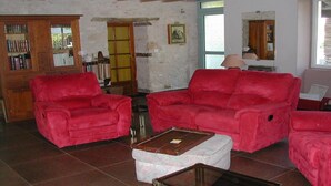 A living room with red sofas, a wooden cabinet with books, and a tiled floor. - Country house Bedroom B (Lasgraisses)