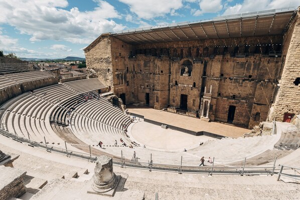 Un anfiteatro antiguo con asientos escalonados y una zona central para el escenario.