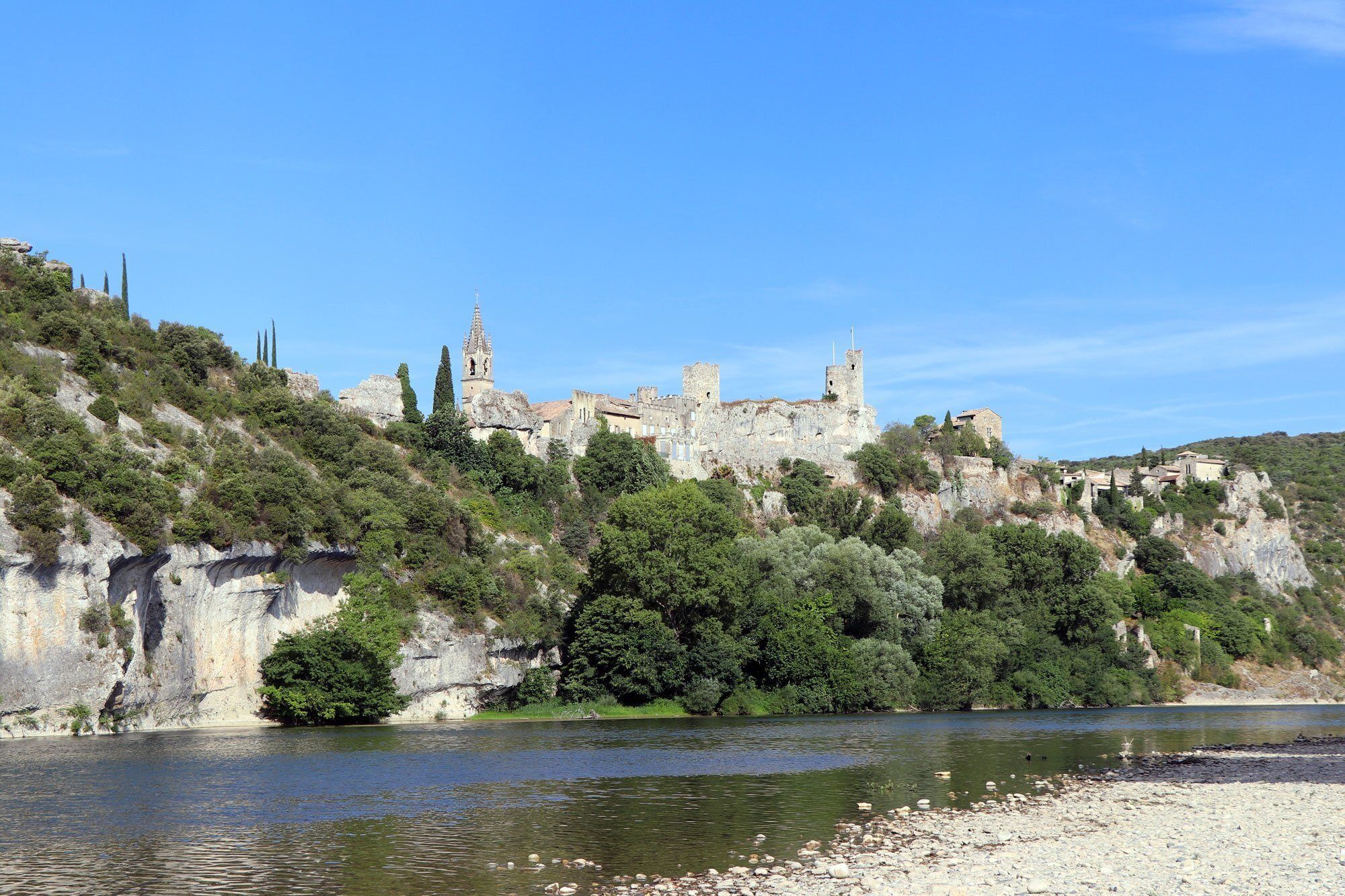 A historic stone castle on a hill overlooking a river.