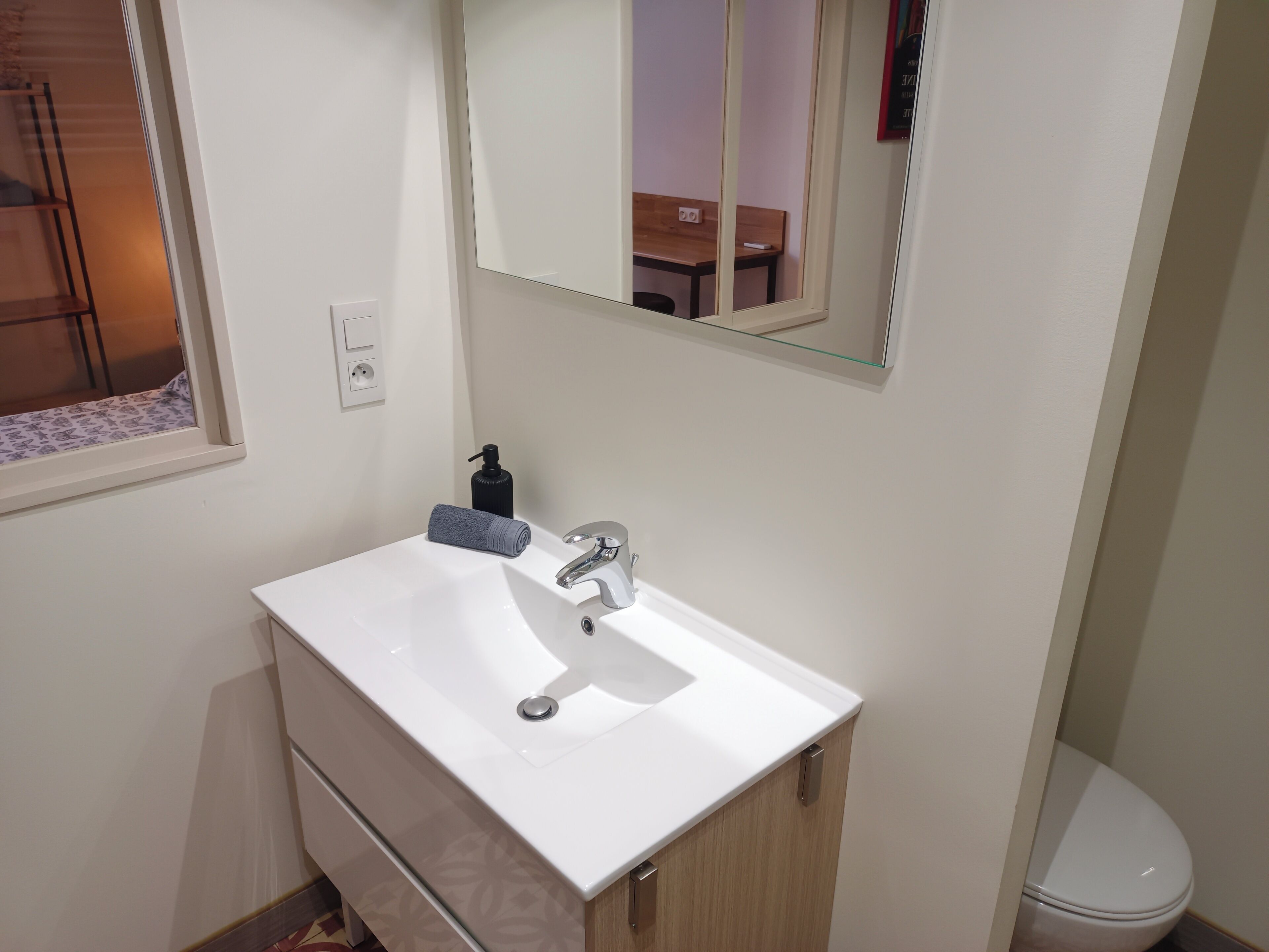 Un baño con un lavabo blanco, un espejo y un inodoro.