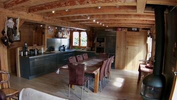 Een gezellig chaletinterieur met een houten plafond, een centraal eiland met zitplaatsen, een fornuis en een keuken met moderne apparatuur.