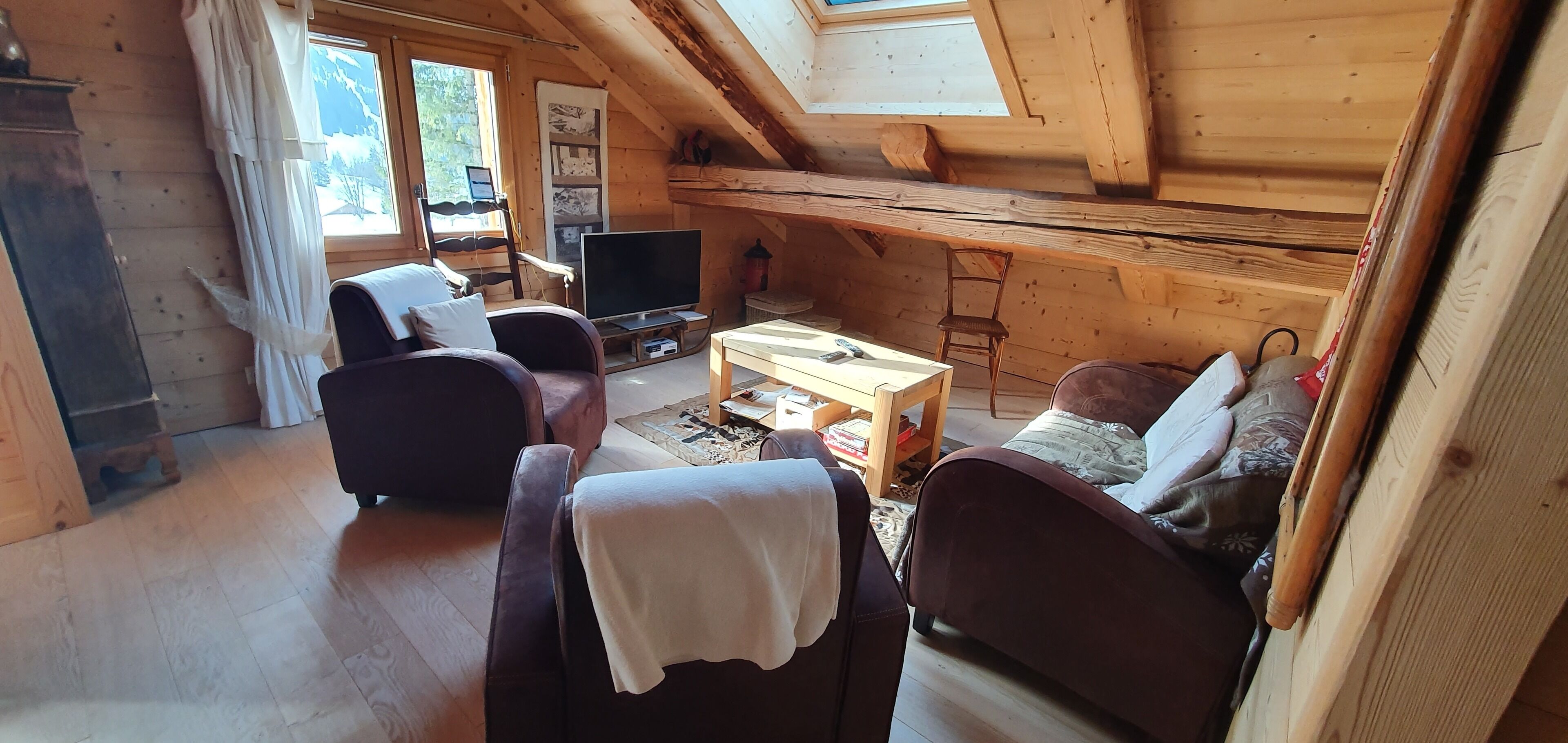 Una cabana de fusta acollidora amb un altell de dormitori, zona de estar amb televisió i taula de dinar.