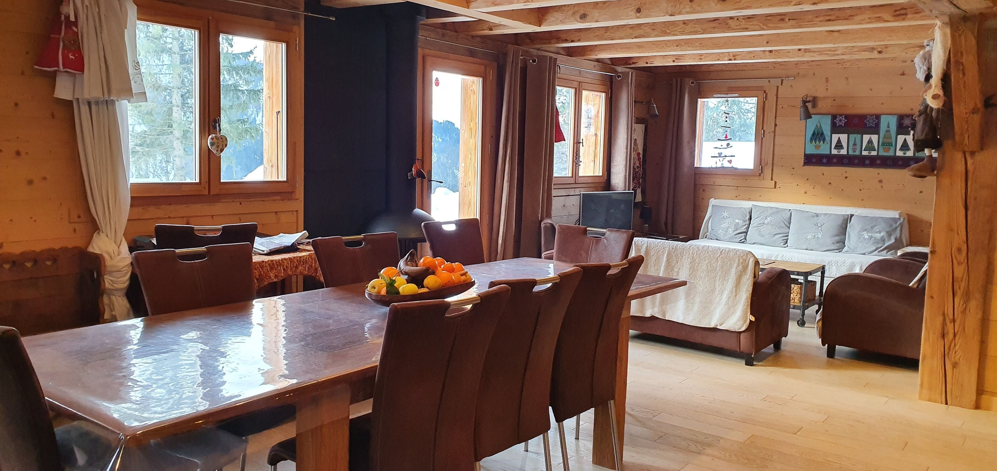 L’intérieur d’un chalet en bois comprend une table à manger, des chaises, un canapé et un téléviseur.