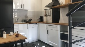A modern kitchen with white cabinets, a black refrigerator, a wooden table, and a black stove. - Arena & Maison Carrée (free parking, fully air-conditioned accommodations) (Nîmes)