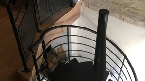 A spiral staircase with a metal railing, a wooden floor, and a lamp on the landing. - Arena & Maison Carrée (free parking, fully air-conditioned accommodations) (Nîmes)