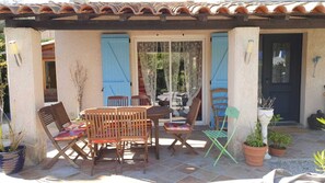 Un patio al aire libre con una mesa y sillas de madera, una puerta azul y plantas en macetas.