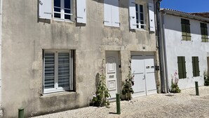 Ein zweistöckiges Gebäude mit weißen Außenwänden, zahlreichen Fenstern mit Fensterläden und einer Schotterauffahrt.