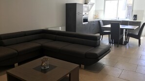Ein modernes Wohnzimmer mit einer Eckcouch, einem Couchtisch und einem Essbereich mit Tisch und Stühlen.
