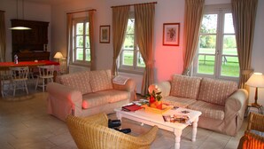 A living room with two sofas, a coffee table, and a dining area with chairs and a table. - Family house in the park with exclusive pool (Vallenay)