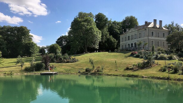 A large, historic building with a symmetrical facade, surrounded by lush greenery and a calm pond. - Family house in the park with exclusive pool (Vallenay)