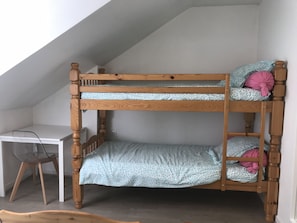 Una litera con escritorio y silla en una habitación con techos inclinados.