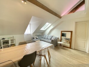 A loft-style room with a dining table, chairs, a sofa, and a small round table with chairs.
