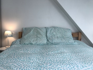 Un dormitorio con cama, mesita de noche y lámpara.