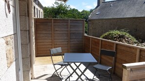 An outdoor patio with a table and chairs, a wooden fence, and a stone wall. - Self catering Pont es omnes Pleurtuit (35) (Pleurtuit)