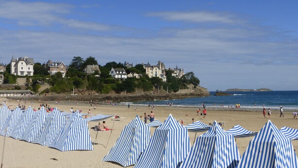 A beach with striped beach umbrellas and houses in the background. - Self catering Pont es omnes Pleurtuit (35) (Pleurtuit)