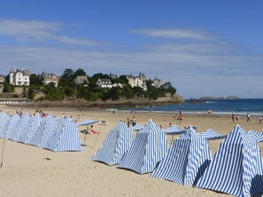 Ein Strand mit gestreiften Sonnenschirmen und Häusern im Hintergrund.