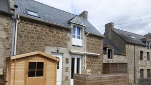 A stone house with a wooden door, a small wooden shed, and a metal fence. - Self catering Pont es omnes Pleurtuit (35) (Pleurtuit)