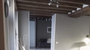 Ein Wohnzimmer mit einer Couch, einer Dekovase und einem Schuhpaar auf dem Boden.