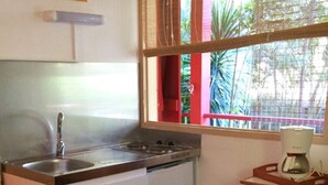 Une petite cuisine équipée d’un évier, d’une cuisinière et d’une machine à café, le tout installé sur une table en bois.