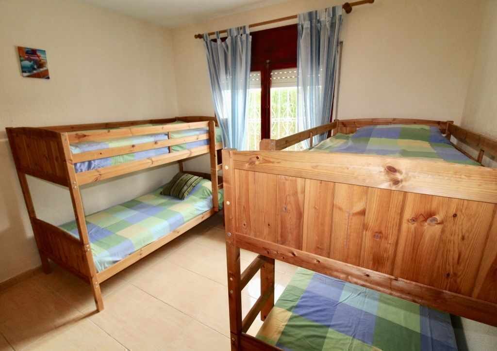 Une chambre avec deux lits superposés, une fenêtre avec des rideaux et un petit tableau accroché au mur.