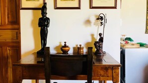 Une table à manger en bois, des chaises, une statue et des tableaux encadrés accrochés au mur.