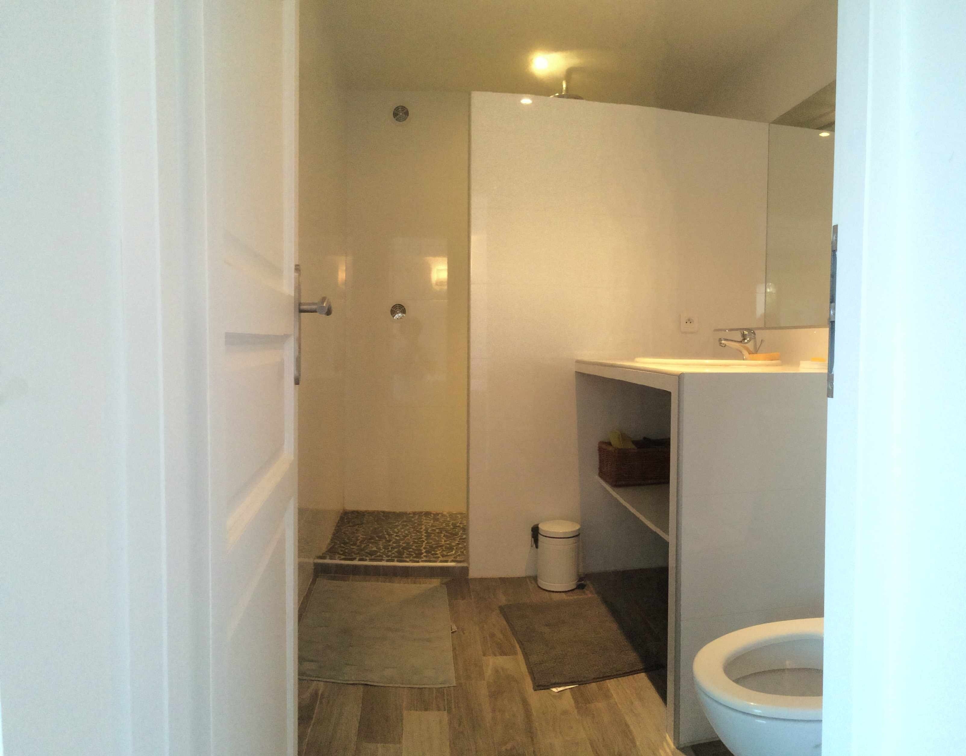 Een badkamer met douche, toilet en wastafel.