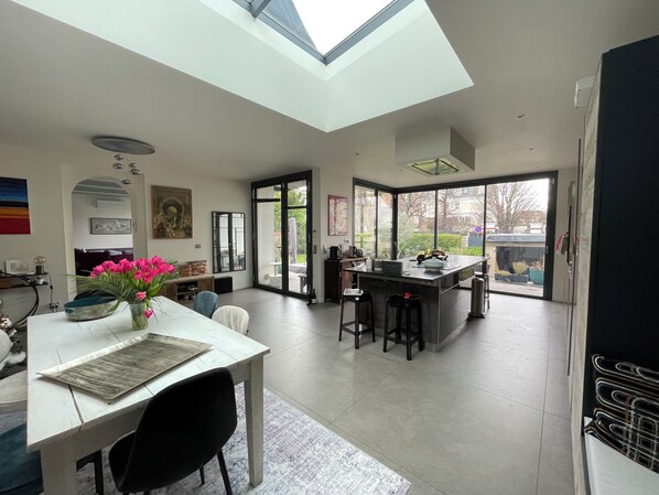 A modern kitchen with a skylight, a dining area with a table and chairs, and a large sliding glass door leading to a patio. - Beautiful house between Paris and Disneyland, sleeps 8, 4 bedrooms - 2 bathrooms (Saint-Maur-Des-Fossés)