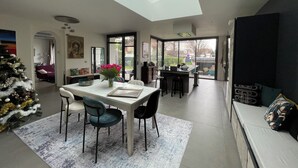 Una cucina moderna con un lucernario, zona pranzo con tavolo e sedie, e un soggiorno con divano.