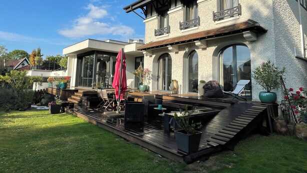 Una casa moderna con una terrazza, ampie finestre e mobili da esterno.