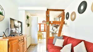 A cozy living room with a red sofa, wooden cabinets, and a TV.