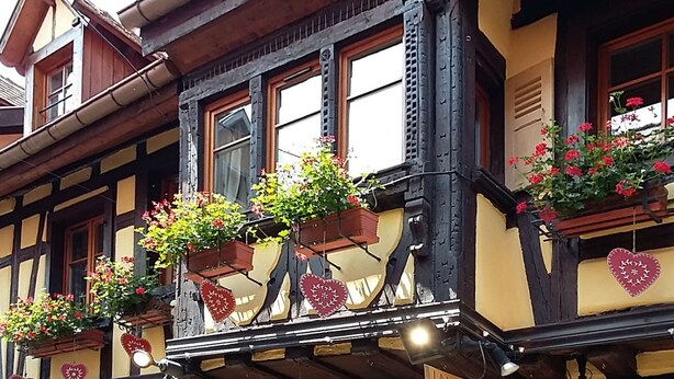 A traditional building with multiple windows, some with flower boxes and heart-shaped decorations.