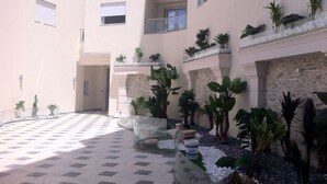 A courtyard with a tiled floor, potted plants, and a stone wall.