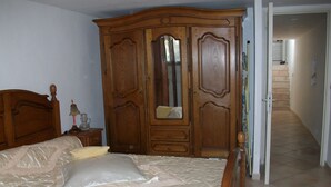 Un dormitorio con un armario grande de madera, una cama con cabecero de madera y un espejo.