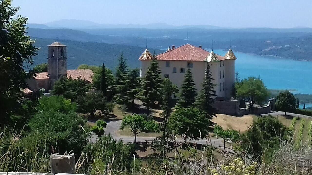 Un castillo con una torre, rodeado de árboles y un lago.
