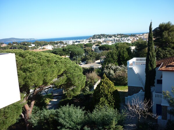 A coastal town with a view of the sea, surrounded by greenery and white buildings with terracotta roofs.