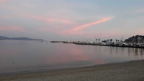 Un rivage paisible, avec un port de plaisance, des bateaux et des bâtiments qui bordent la côte.
