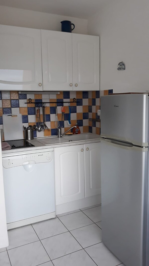 A compact kitchen with white cabinets, a stainless steel refrigerator, a tiled backsplash, and a small coffee maker on the countertop. - Studio Sea Cavalaire Ocean View (Cavalaire-Sur-Mer)