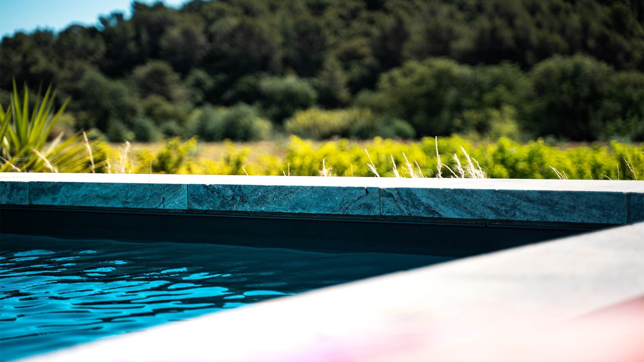 Una piscina con una vista despejada del agua y un borde de piedra.