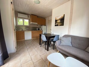 Cozy living space with a kitchenette and seating area, featuring a sofa, table, chairs, microwave, refrigerator, and dishwasher.