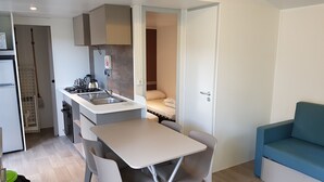 Uma cozinha compacta com área de refeições, um sofá e porta que dá para um quarto.
