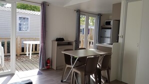 Espaço compacto com cozinha compacta, área de refeições com mesa e cadeiras, uma pequena mesa branca e um extintor de incêndio.