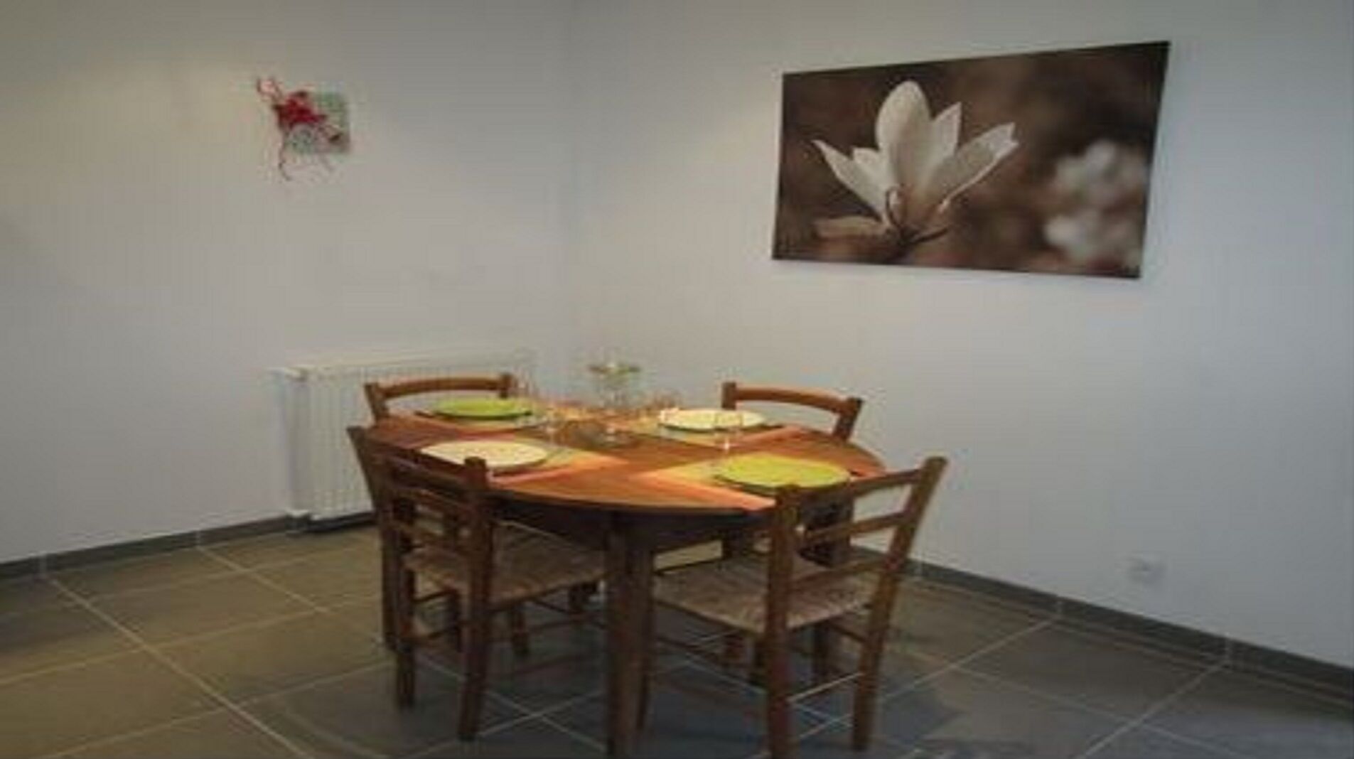 Een eethoek met een ronde houten tafel, vier stoelen en een enkele bloevas.