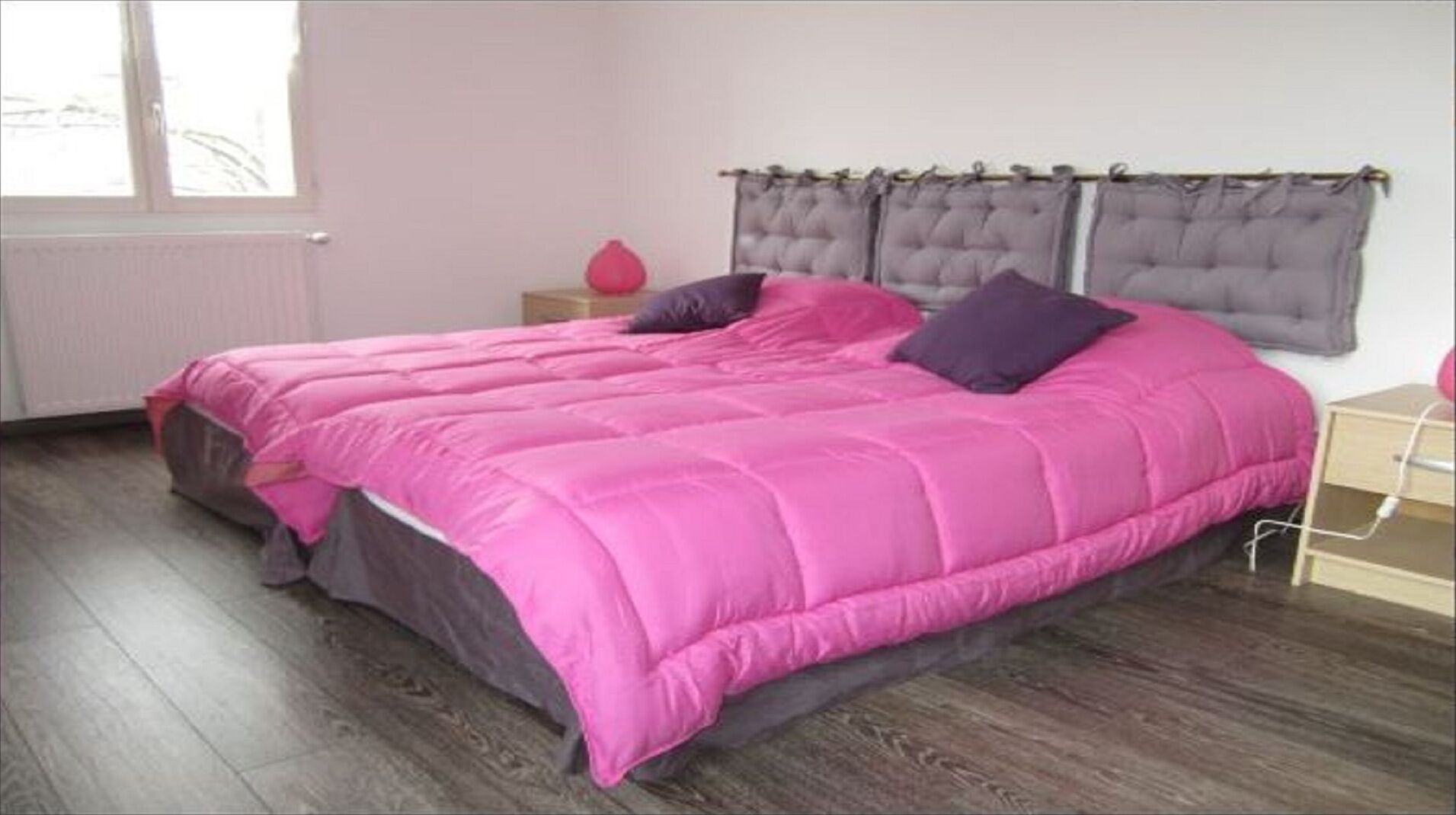 Quarto com uma cama grande, mesa de cabeceira, cômoda e janela com cortinas.