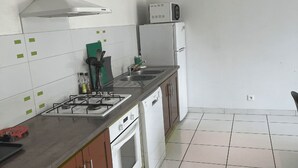 A kitchen with a gas stove, microwave, sink, and white cabinets. - Our gîtes are ideally located in Pontonx-sur-l'Adour (PONTONX-SUR-L'ADOUR)