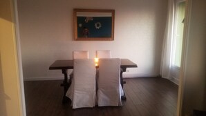 Un coin repas avec une table et des chaises, un tableau accroché au mur et une fenêtre avec des rideaux.