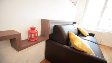 Un salon moderne avec un canapé en cuir marron, deux coussins jaunes, une lanterne rouge et une étagère en bois.