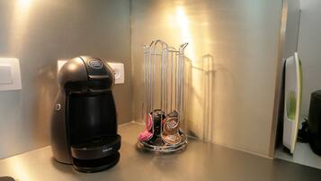 A coffee maker and a coffee pod holder on a stainless steel countertop.